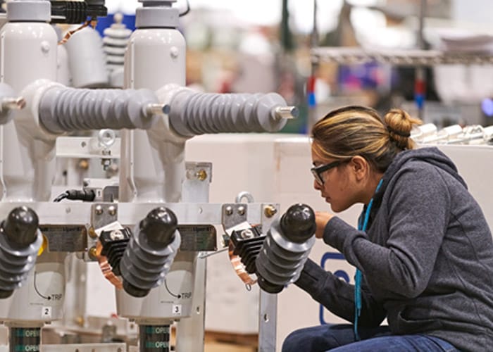 A woman inspecting a Viper ST recloser in a factory.