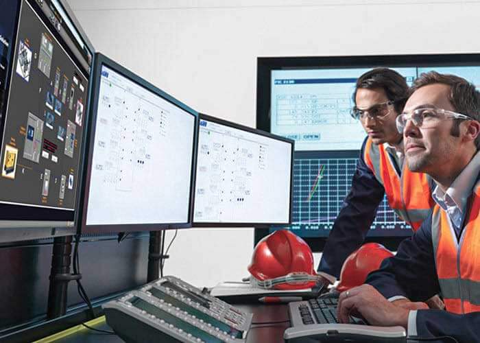 Two engineers looking at a computer screen in a control center.