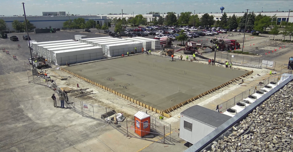 Equipe de construção inspecionando uma fundação de concreto concluída para a instalação de um sistema de armazenamento de energia de bateria.