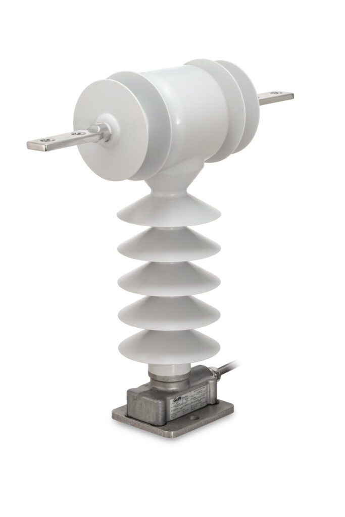 A white electrical insulator with multiple disc-shaped sections, mounted on a metal base with a wire connected to it.